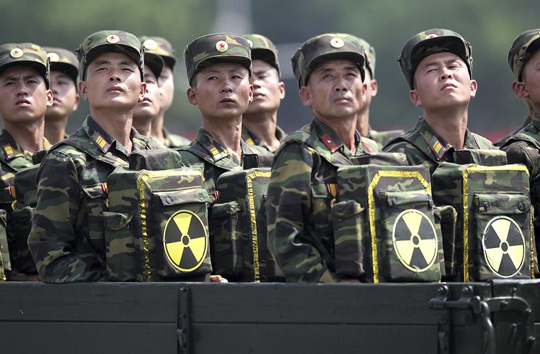 جنود كوريا الشمالية يتحولون ويتطلعون إلى زعيمهم كيم جونغ أون من مركبة موكب عسكري وهم يحملون عبوات تحمل الرمز النووي خلال احتفال بالذكرى الستين لهدنة الحرب الكورية في بيونغ يانغ، كوريا الشمالية، 27 يوليو / تموز 2013